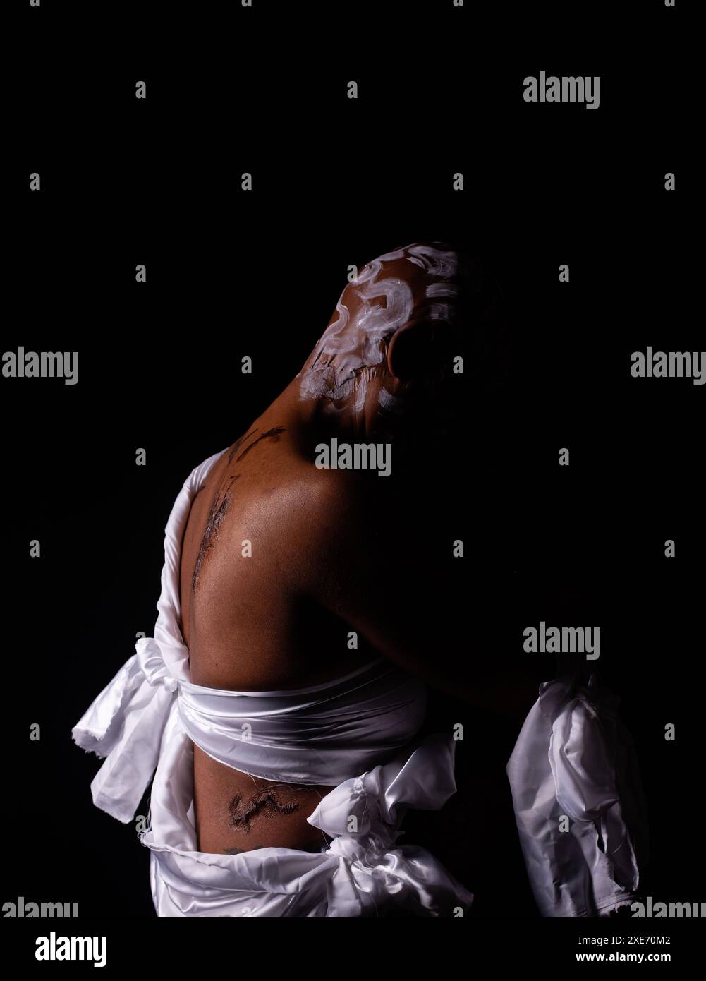 Rasierte und vernarbte Frau in dezenter Beleuchtung, die den Missbrauch schwarzer Frauen darstellt. Stockfoto