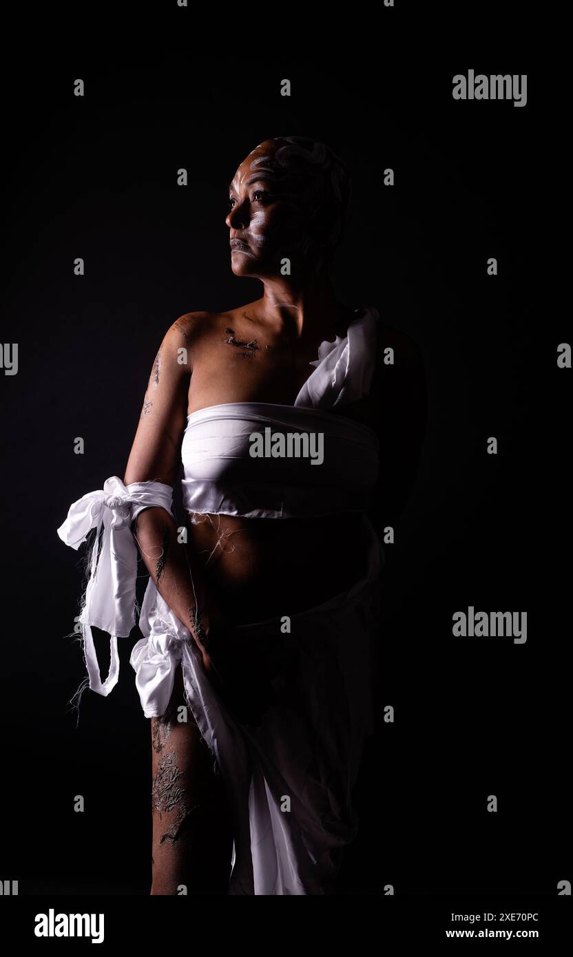 Rasierte und vernarbte Frau in dezenter Beleuchtung, die den Missbrauch schwarzer Frauen darstellt. Stockfoto