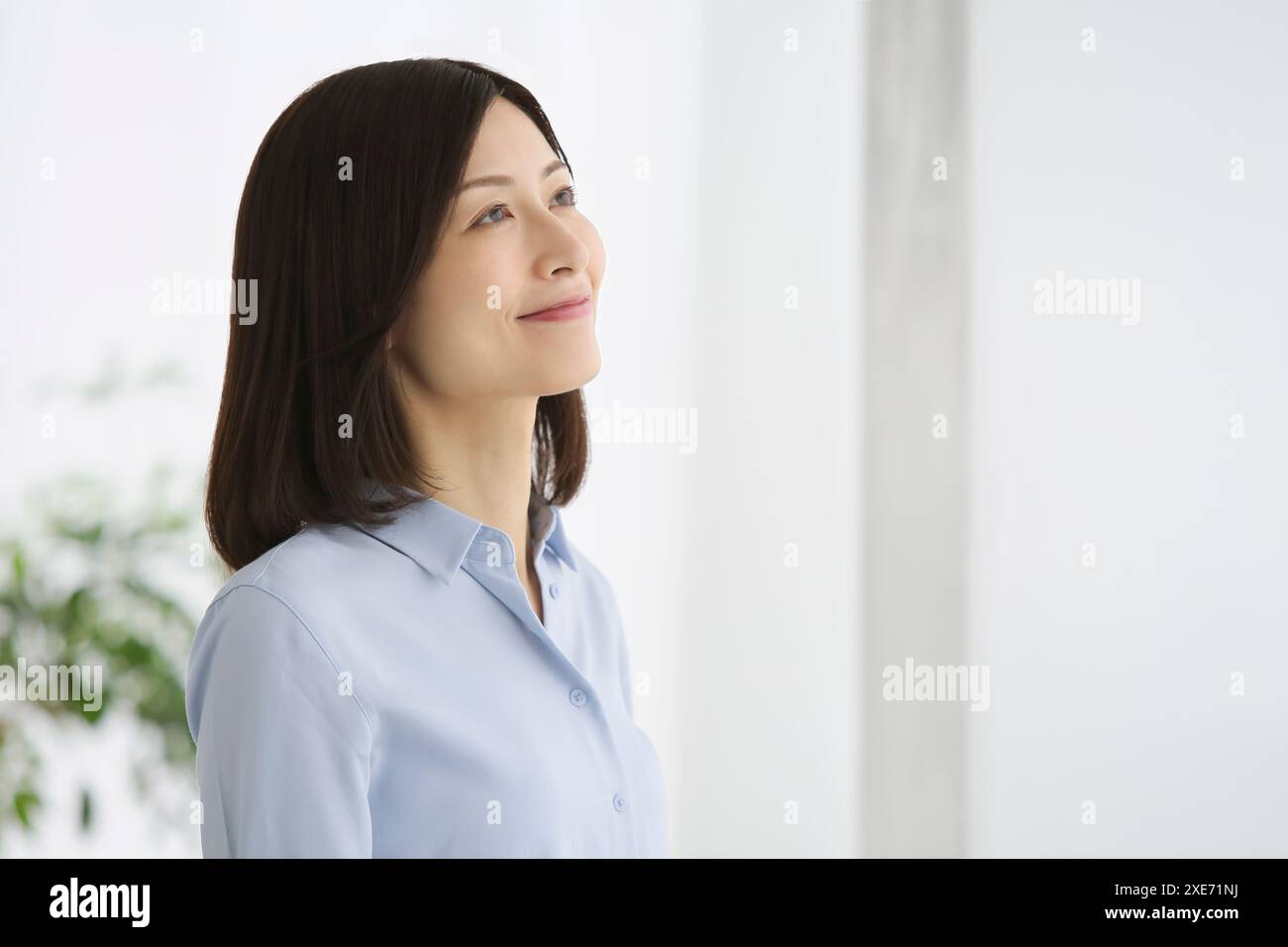 Erwachsene Frau, die am Fenster steht. Stockfoto