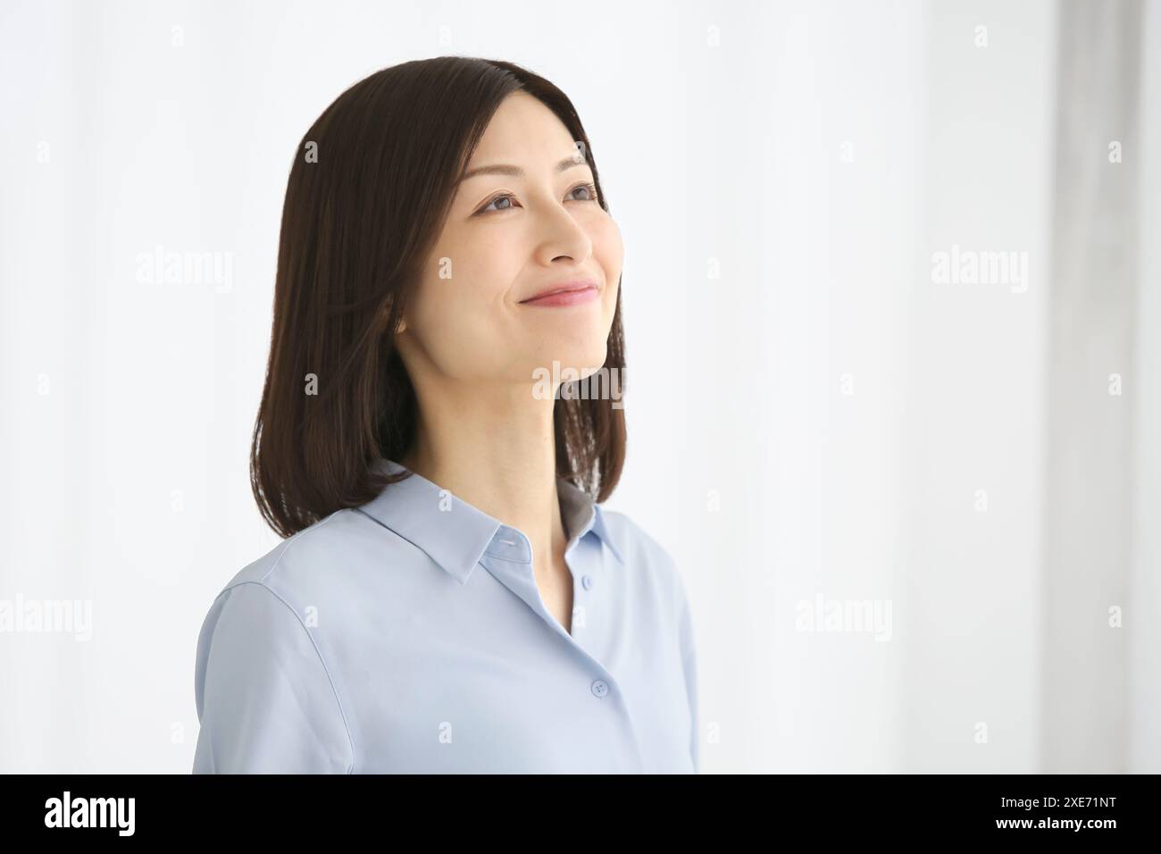 Erwachsene Frau, die am Fenster steht. Stockfoto