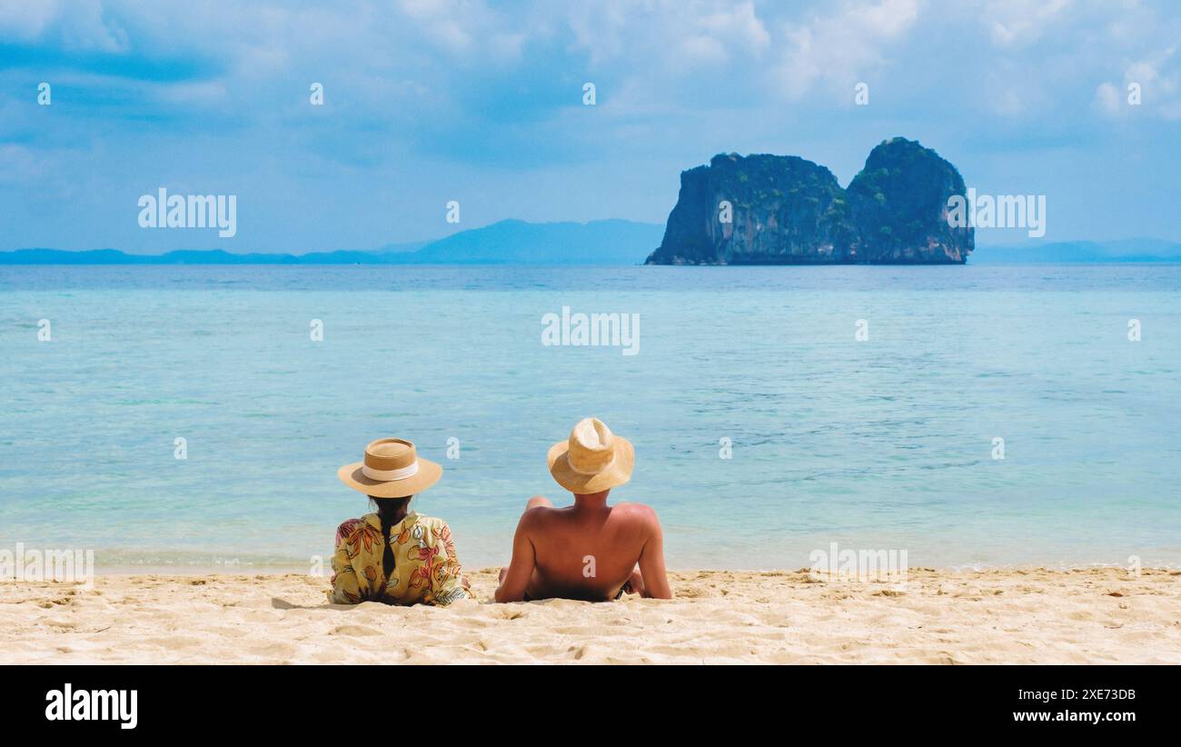Ein paar Männer und Frauen sitzen am tropischen Strand auf der Insel Koh Ngai Stockfoto