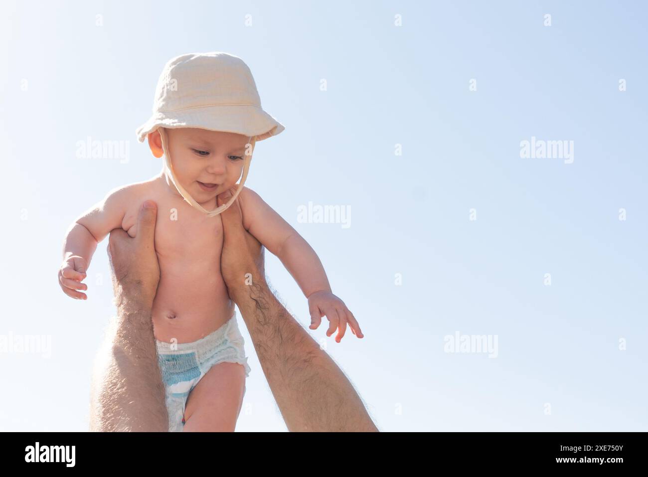 Vater und Baby spielen unter einem sonnigen Himmel, ein aufbauender Moment. Väterliche Freude und kindliche Unschuld Stockfoto