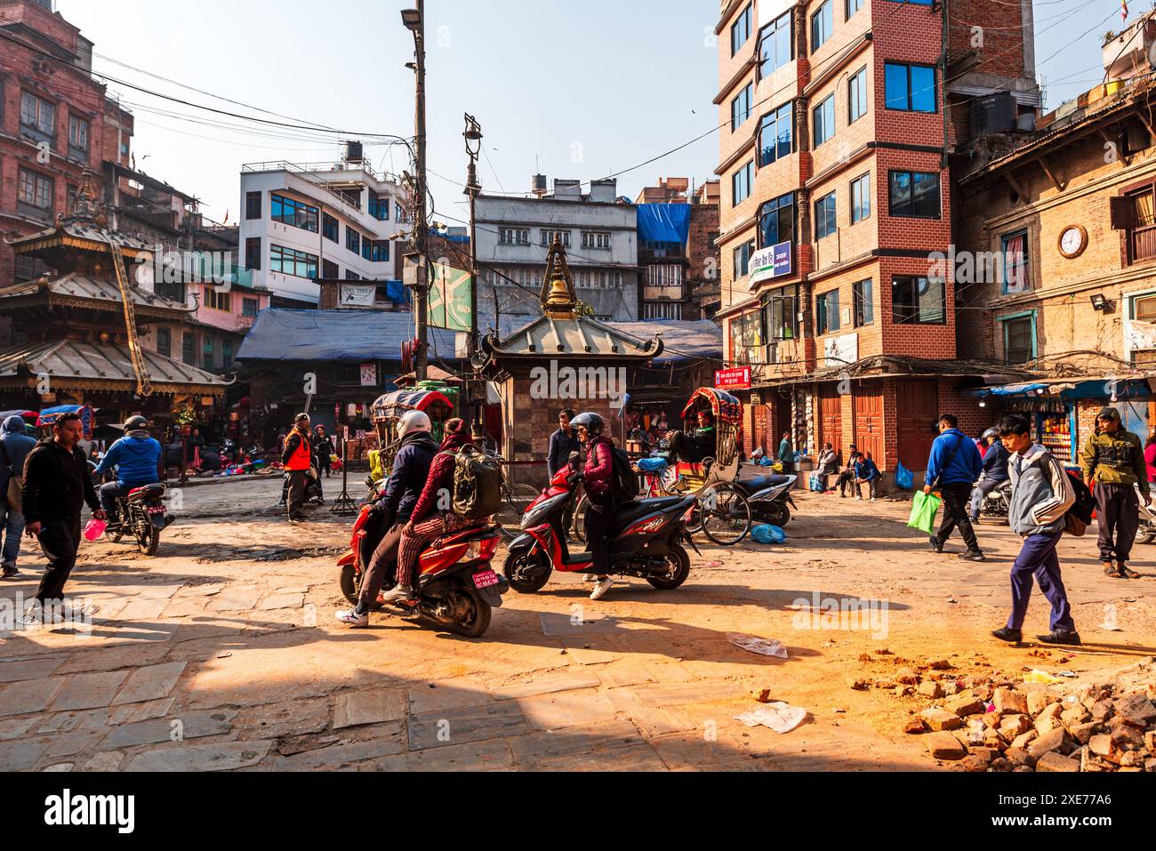 Viel Verkehr mit Motorrädern und Fußgängern auf einer staubigen Marktstraße, warmes Licht der morgendlichen Hauptverkehrszeit, Kathmandu, Nepal, Asien Stockfoto