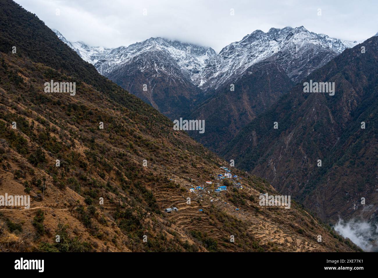 Blick auf das weite Tal mit hoch aufragenden schneebedeckten Bergen und Sherpagaon Dorf auf den Pisten, die Langtang Valley Trek, Himalaya, Nepal, Asien Stockfoto