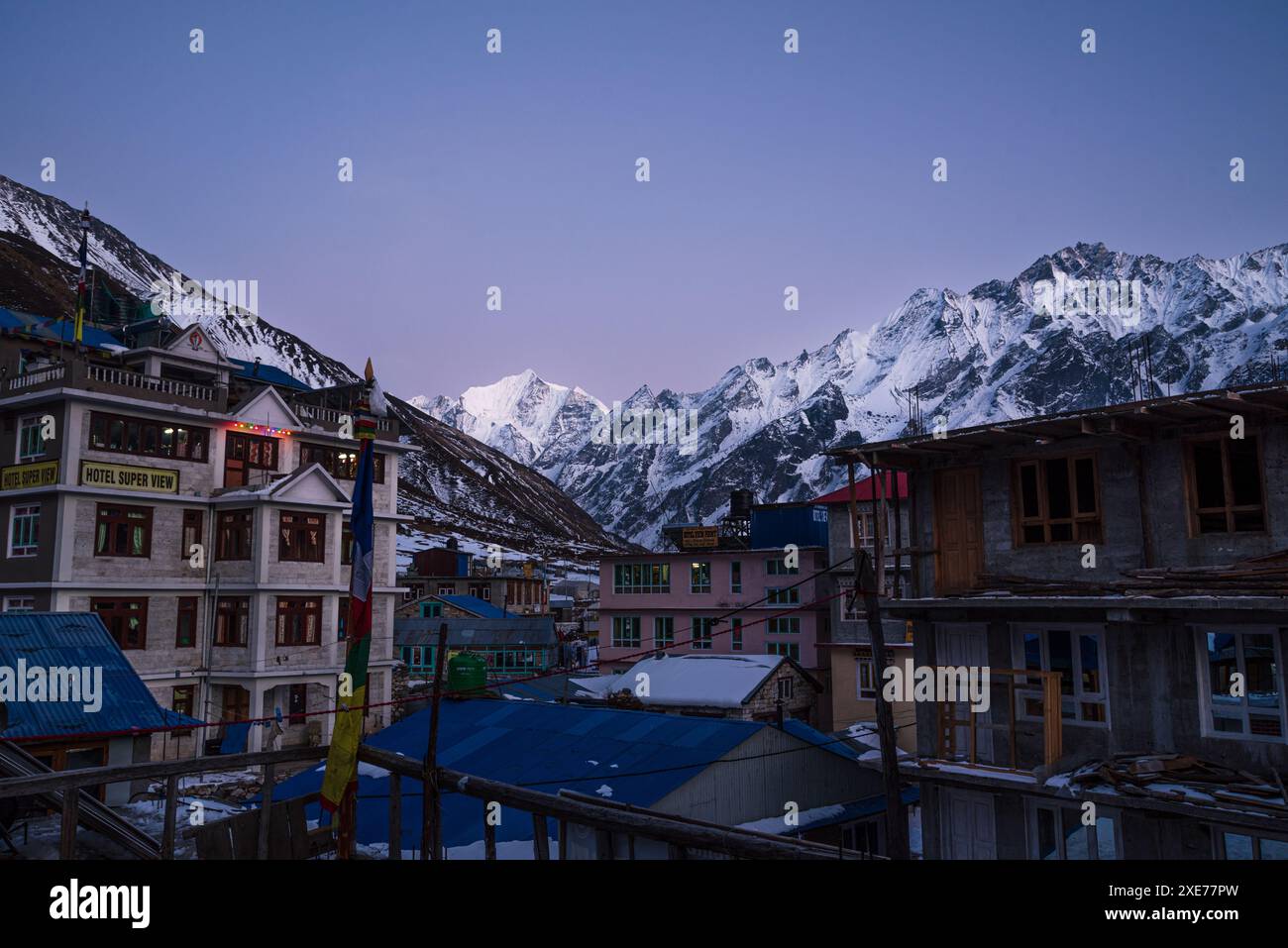 Blick über die Stadt Kyanjin Gompa mit sanftem lila Licht nach Sonnenuntergang und schneebedecktem Gipfel von Gangchempo, lang Tang Valley Trek, Himalaya, Nepal, Asien Stockfoto