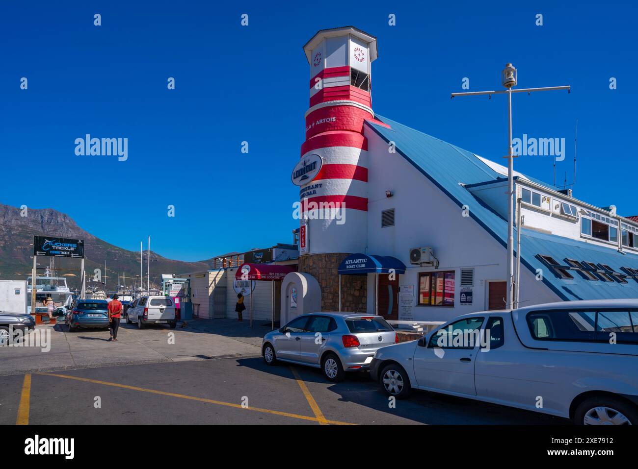 Blick auf die farbenfrohe Bar und den Leuchtturm in Hout Bay Harbour, Hout Bay, Kapstadt, Westkap, Südafrika, Afrika Stockfoto