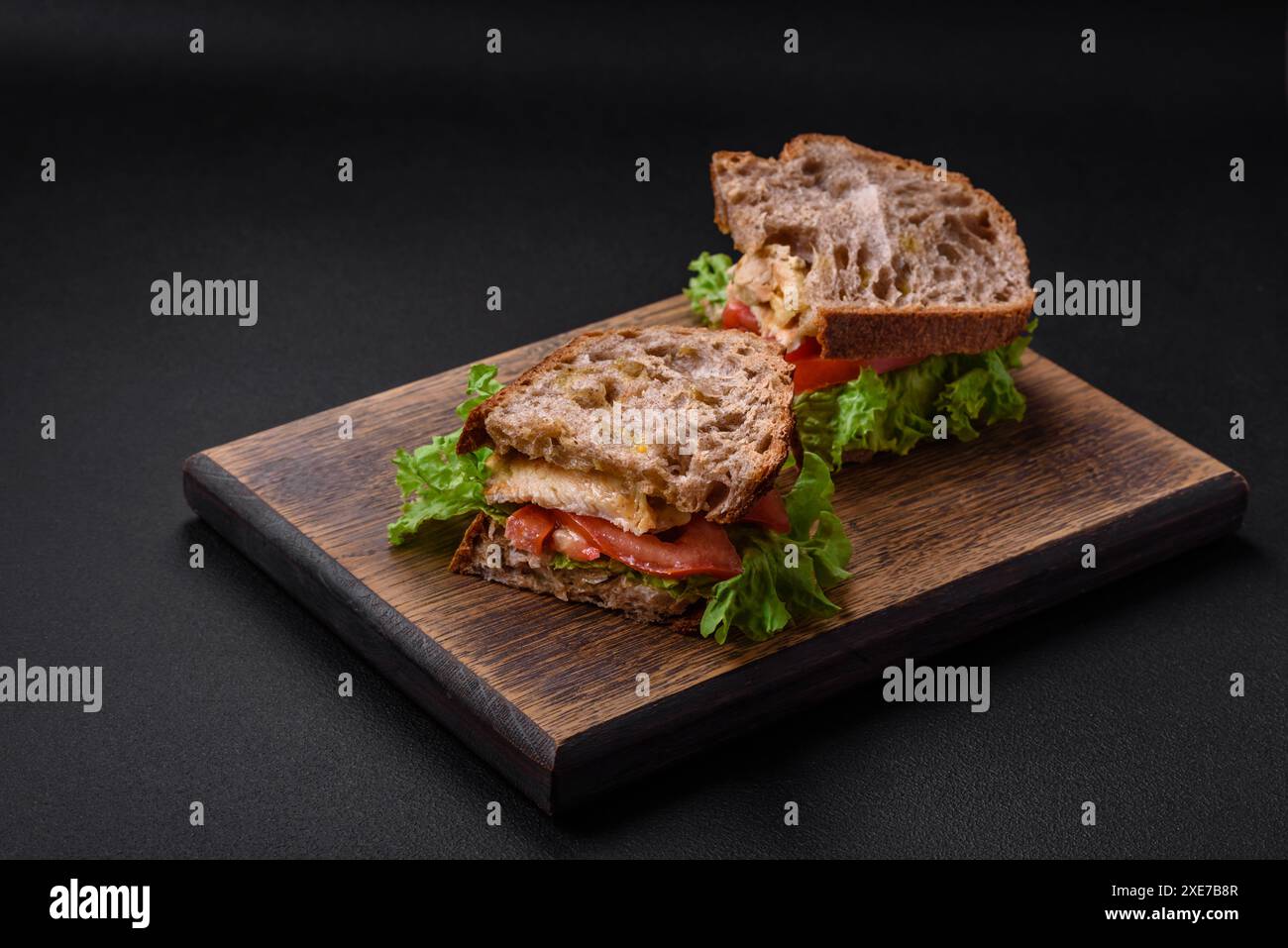 Köstliches Sandwich mit knusprigem Toast, Huhn, Tomaten und Salat Stockfoto