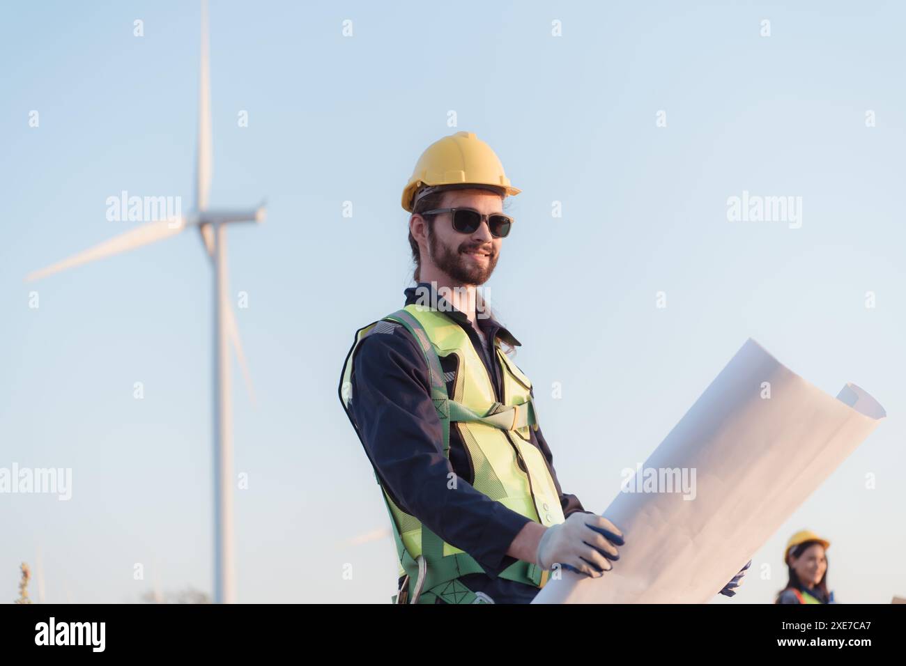 Junger Ingenieur mit Schutzhelm und Blaupause in der Windenergieanlage. Stockfoto