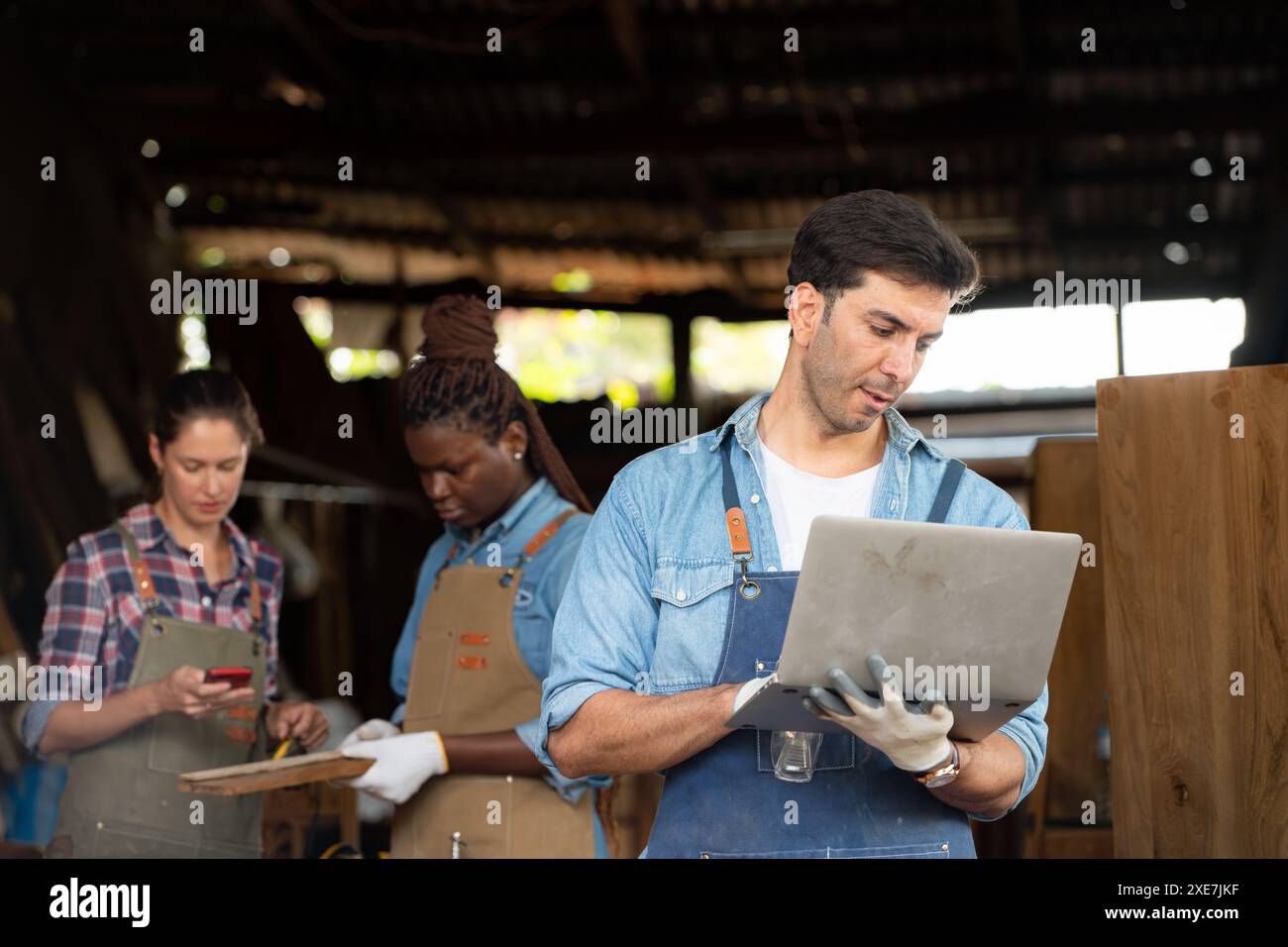 Porträt eines Zimmermanns, der mit Laptop in der Werkstatt steht Stockfoto