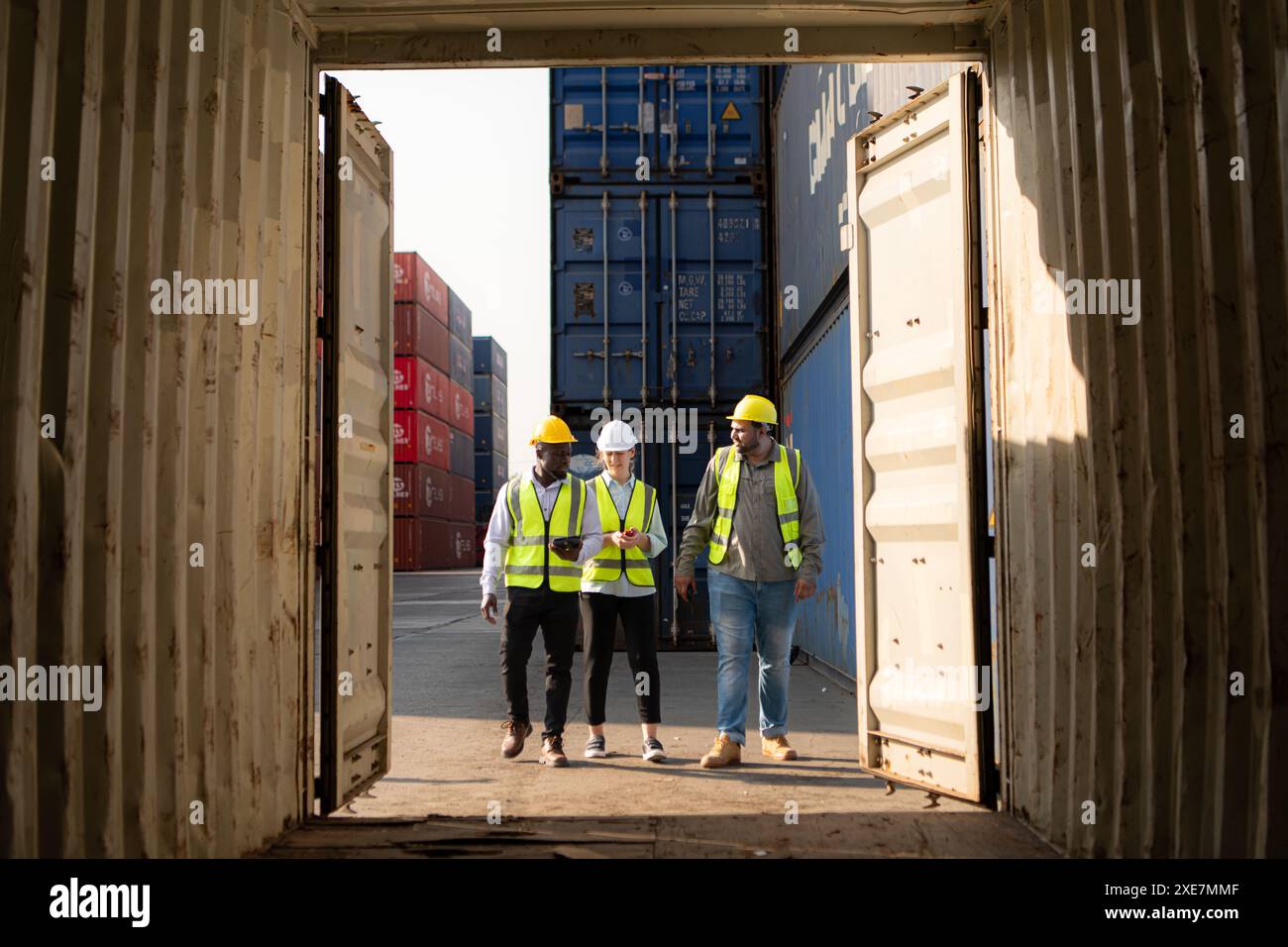 Gruppe von Arbeitnehmern in einem leeren Containerlagerplatz wird der Zustand des alten Containers geprüft, um festzustellen, ob ich Stockfoto