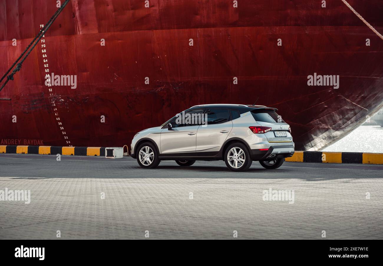 Silver SEAT Arona parkte am Rumpf eines riesigen Schiffes in einem Hafen. Dreiviertel-Rückansicht der spanischen Fließheck-Überkreuzung Stockfoto