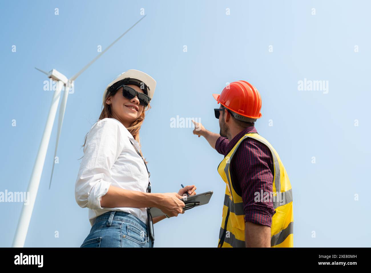 Ingenieur und Architekt diskutieren über eine Windkraftanlage mit blauem Himmel Hintergrund Stockfoto