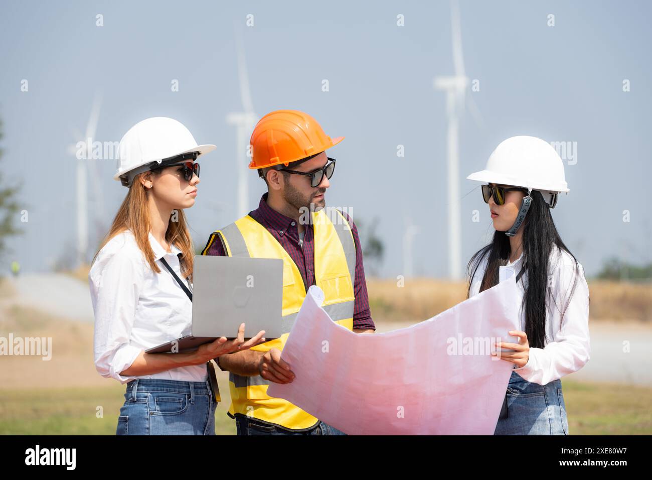 Gruppe von Ingenieuren und Architekten auf der Baustelle mit Windturbinen im Hintergrund Stockfoto