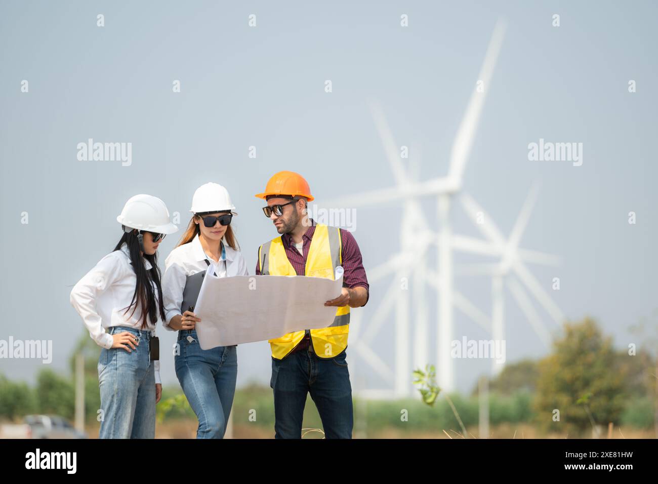 Gruppe von Ingenieuren und Architekten auf der Baustelle mit Windturbinen im Hintergrund Stockfoto