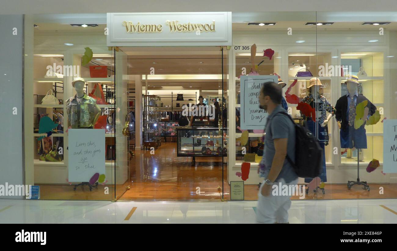 Fußgänger spazieren vorbei am britischen multinationalen Modegeschäft Vivienne Westwood und einem Geschäft in Harbour City in Hong Kong, China Stockfoto