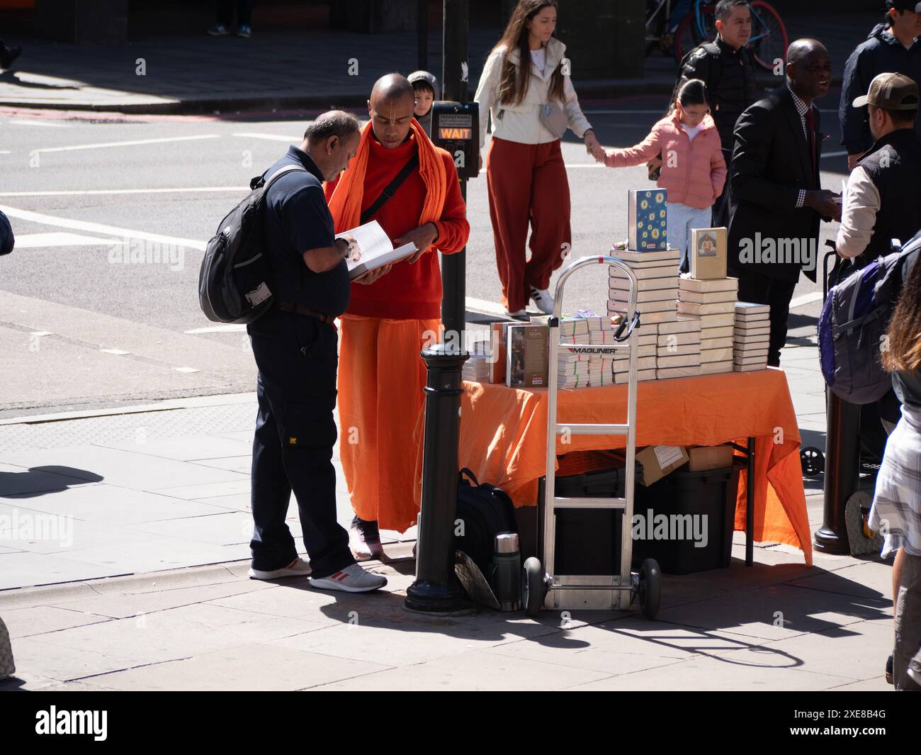 Hare Krishna-Anhänger zeigen religiöse Bücher an Fußgänger im Zentrum Londons Stockfoto