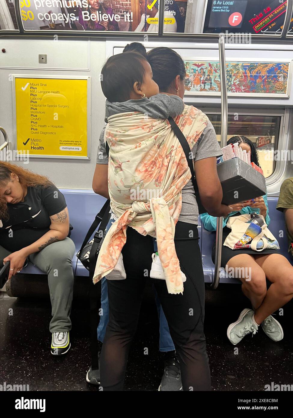 Undokumentierte Frau mit Baby auf dem Rücken verkauft Süßigkeiten in einer New York City U-Bahn. Obwohl offiziell illegal, scheinen die Behörden diese Praxis zu übersehen. Stockfoto