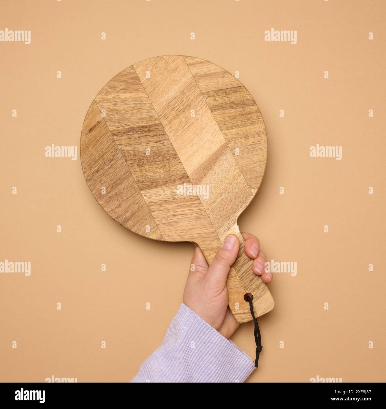 Die Hand der Frau hält ein leeres rundes Holzschneidebrett Stockfoto