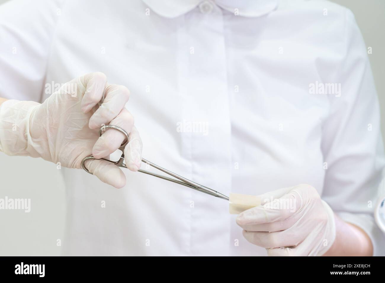 Arzt mit Handschuhen mit einer chirurgischen Pinzette zum Öffnen der Bandhilfe Stockfoto