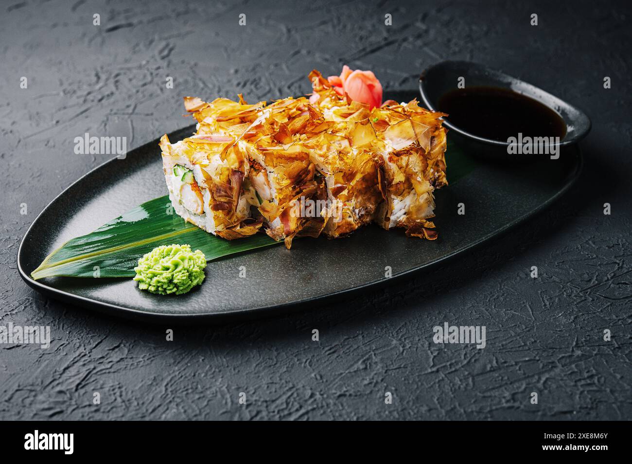 Sushi-Bonito-Rolle auf einem dunklen Teller Stockfoto