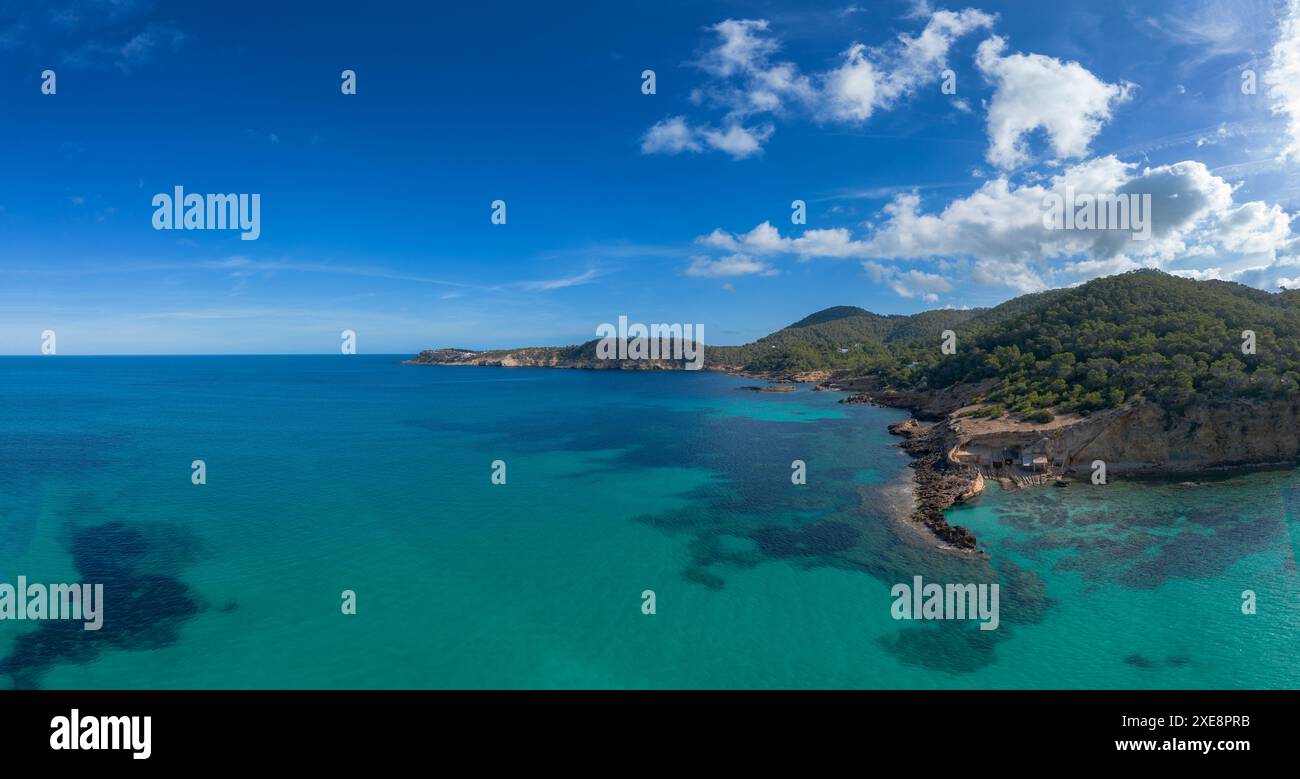 Die grüne und zerklüftete hügelige Küste von Nord-Ibiza mit Blick auf das türkisfarbene Wasser der Bucht Cala Xarraca Stockfoto