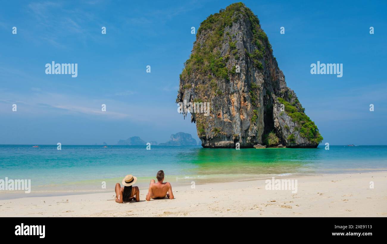 Zwei Personen genießen den Blick auf das Meer und den großen Felsen am Strand in Thailand Stockfoto