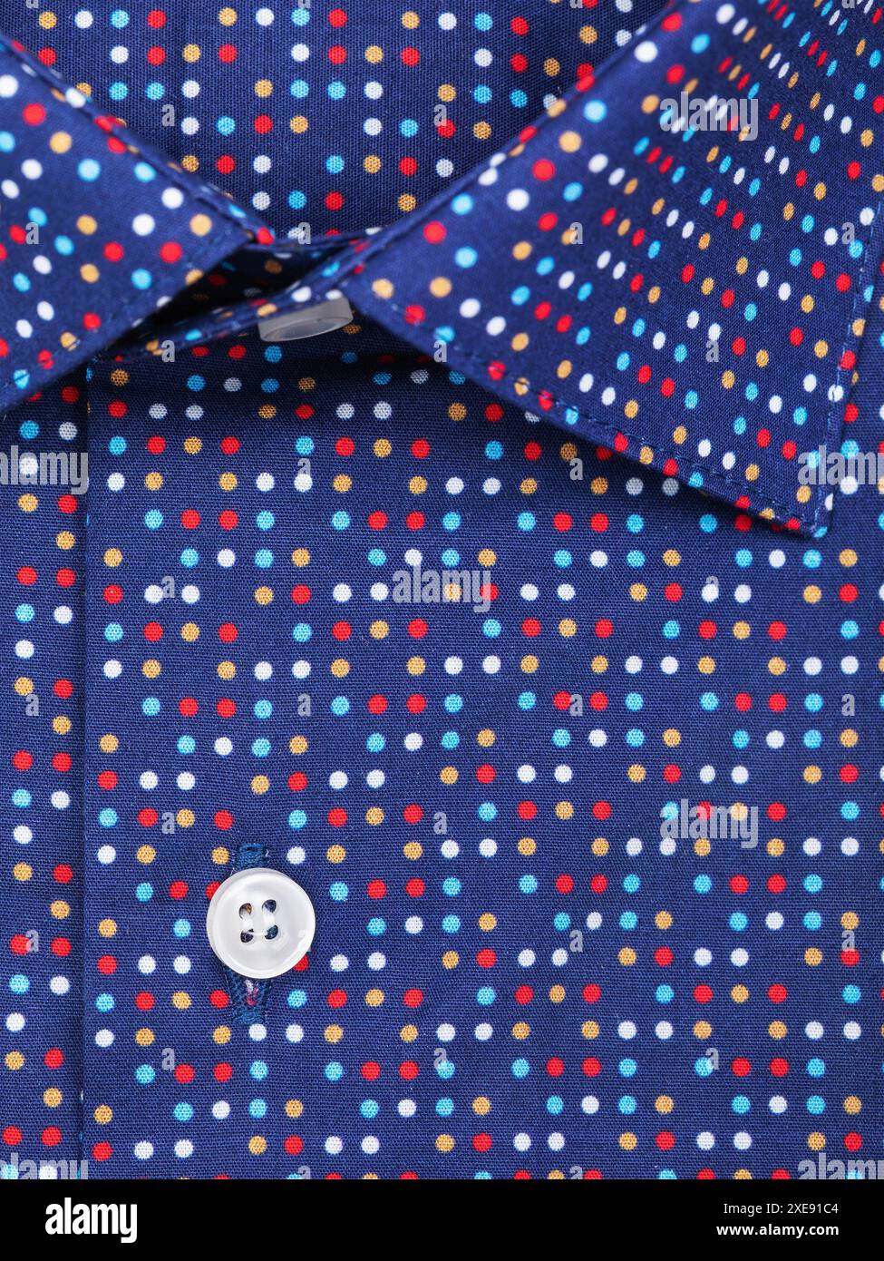 Nahaufnahme einer Knopfleiste auf einem dunkelblauen Herrenhemd mit farbigen Polka Dots Stockfoto