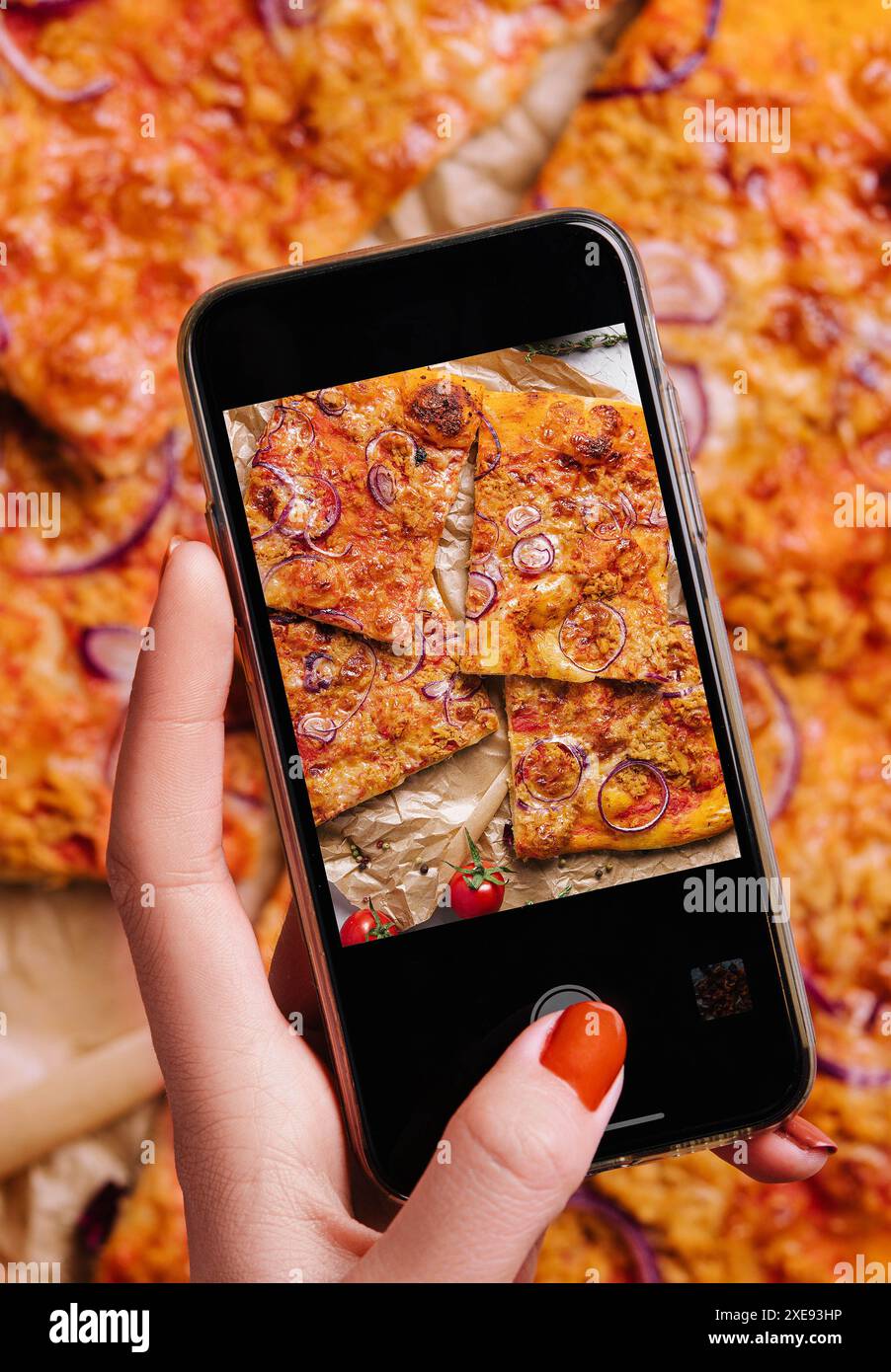 Weibliche Hand macht ein Foto von Pizza mit einem Handy Stockfoto