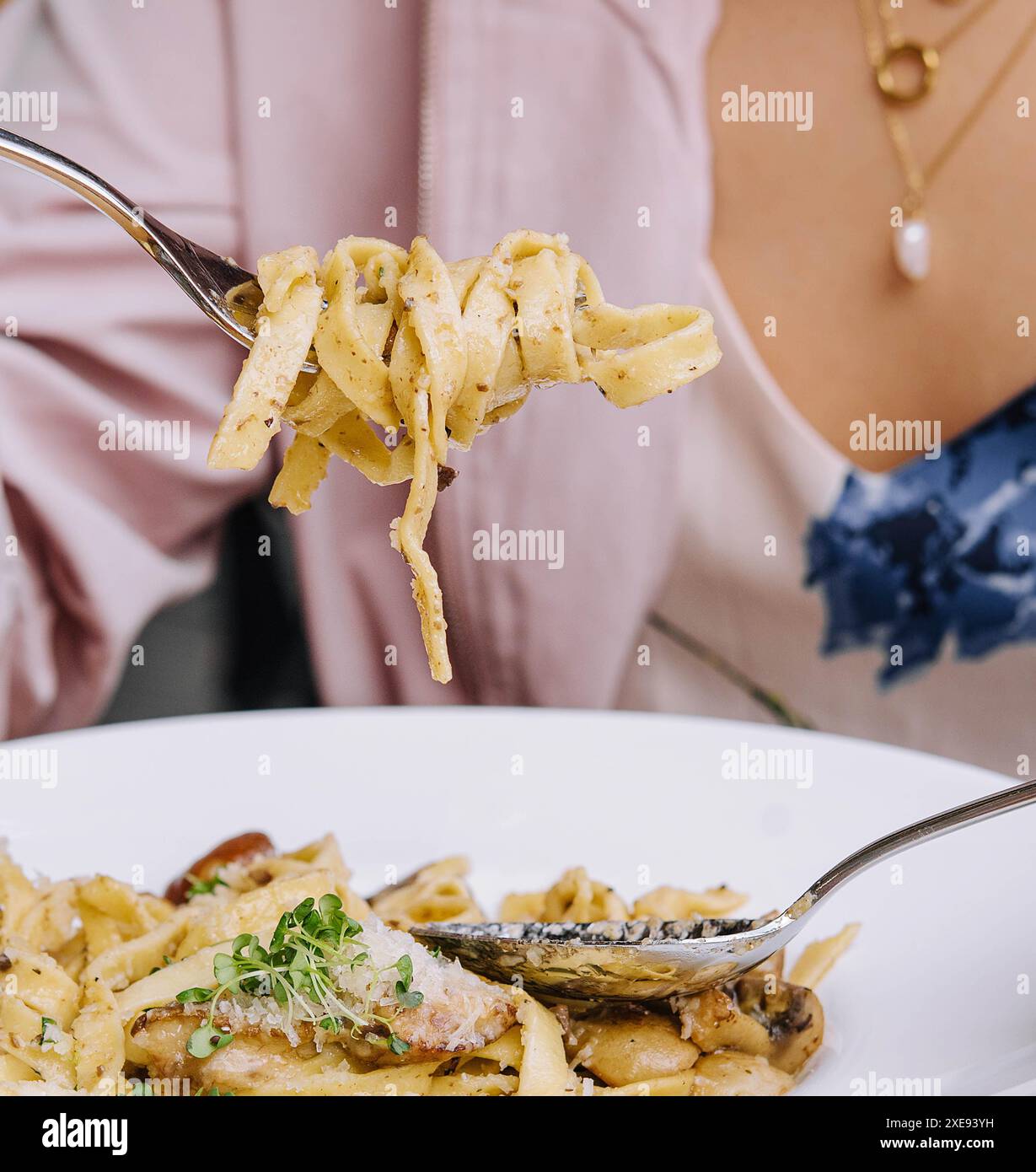 Frau isst Pasta mit Pilzen auf Holztisch Stockfoto