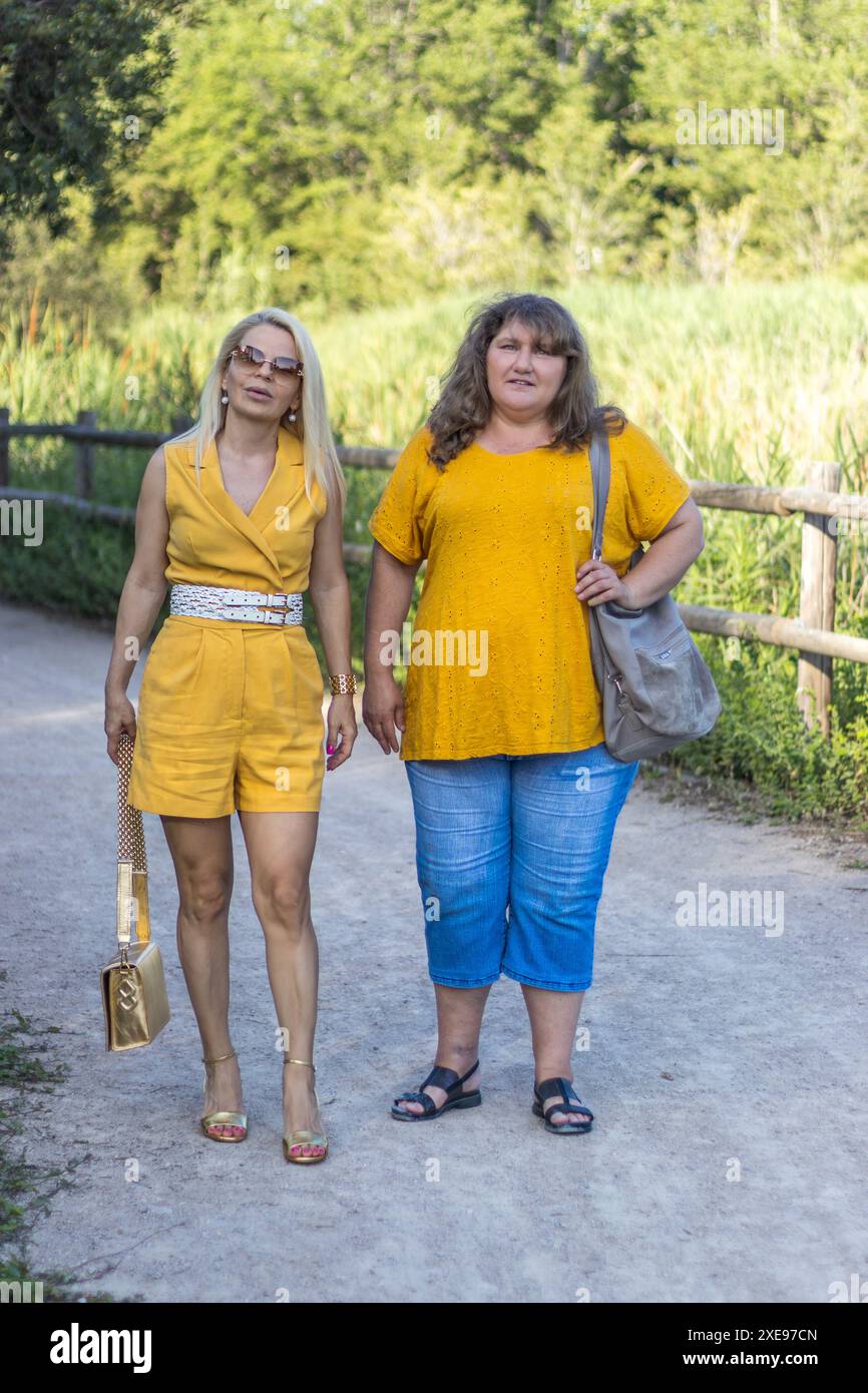 Dieses Bild zeigt zwei blonde Frauen in Gelb, die einen gemütlichen Spaziergang durch den Park genießen. Stockfoto