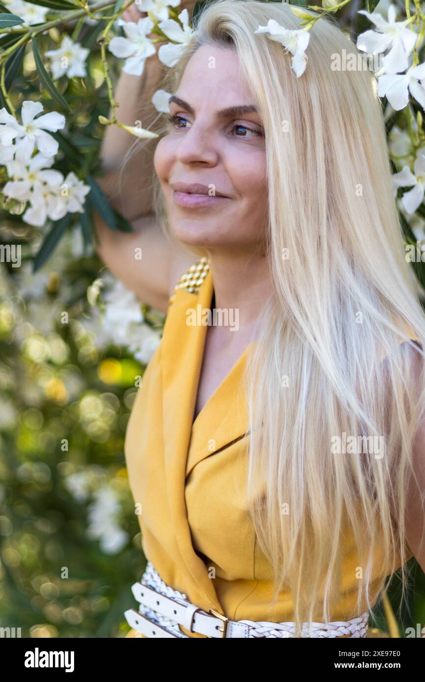 Dieses Bild fängt eine Frau mit zartem Make-up, gut gestylten blonden Haaren und warmbraunen Augen ein. Stockfoto