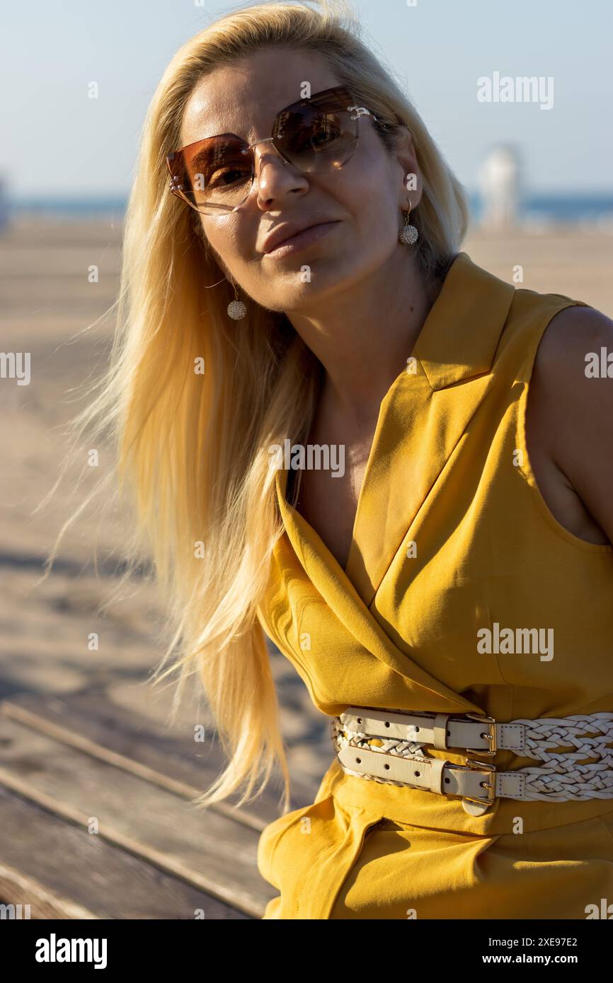 Dieses Bild fängt eine Frau mit zartem Make-up, gut gestylten blonden Haaren und warmbraunen Augen ein. Stockfoto