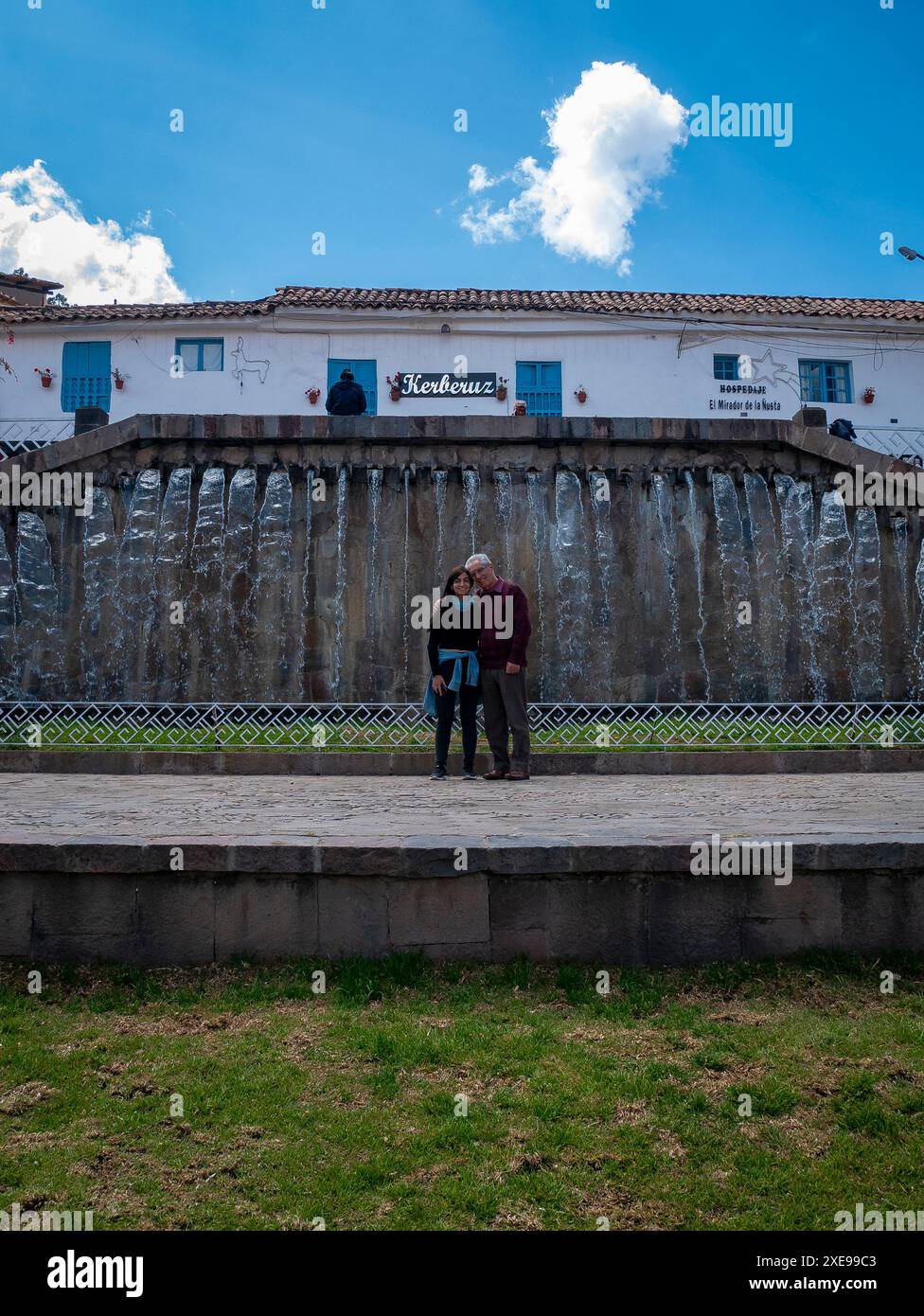 Cusco, Peru – 9. August 2023: Schwarzhaarige Frau posiert mit ihrem Vater vor einem Brunnen in Barrio de San Blas Stockfoto