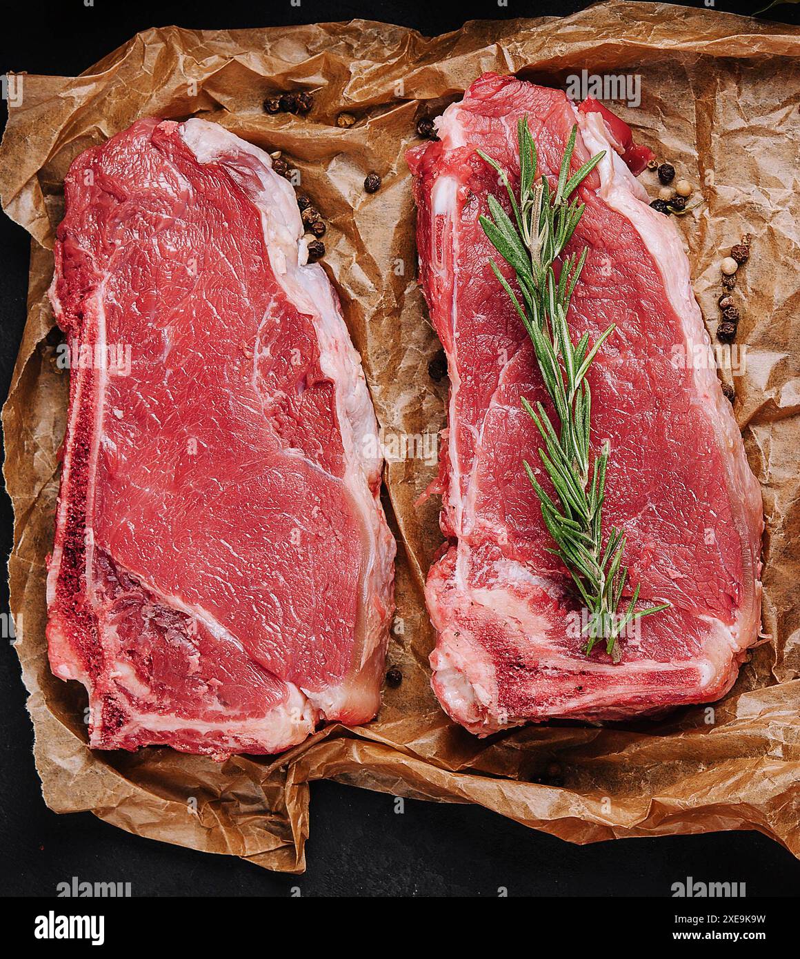 Rohe Streifen-Steaks auf Backpapier Stockfoto