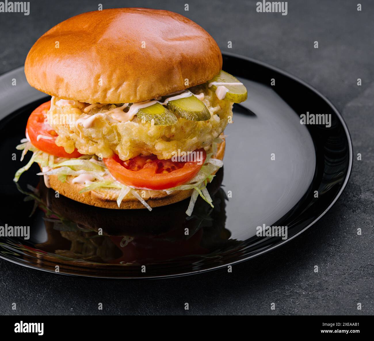 Gebratener Fisch Filet Burger auf schwarzem Teller Stockfoto