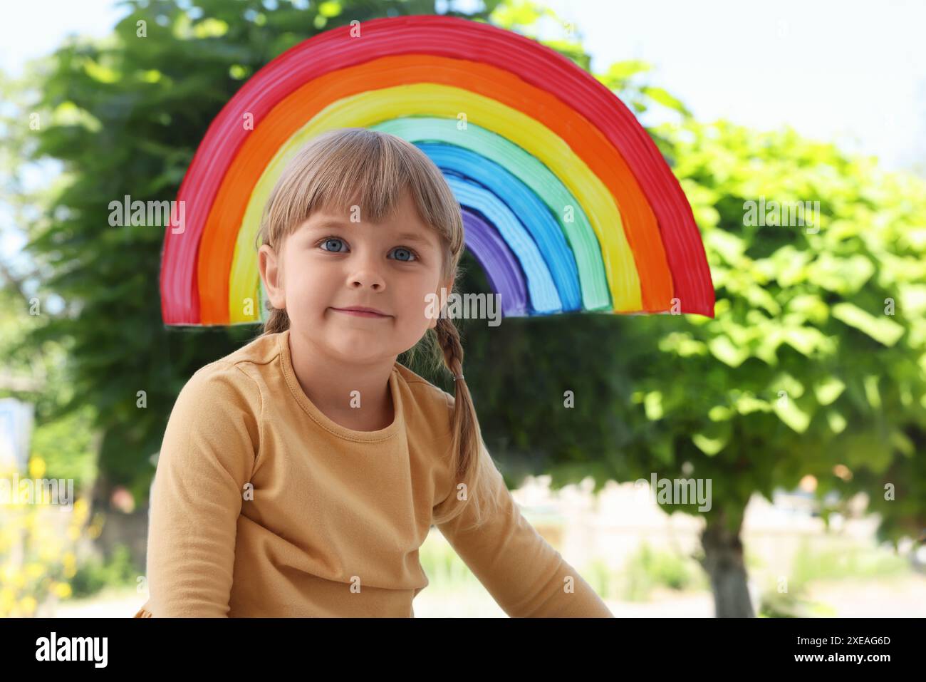 Ein kleines Mädchen in der Nähe von Regenbogenmalerei am Fenster drinnen Stockfoto