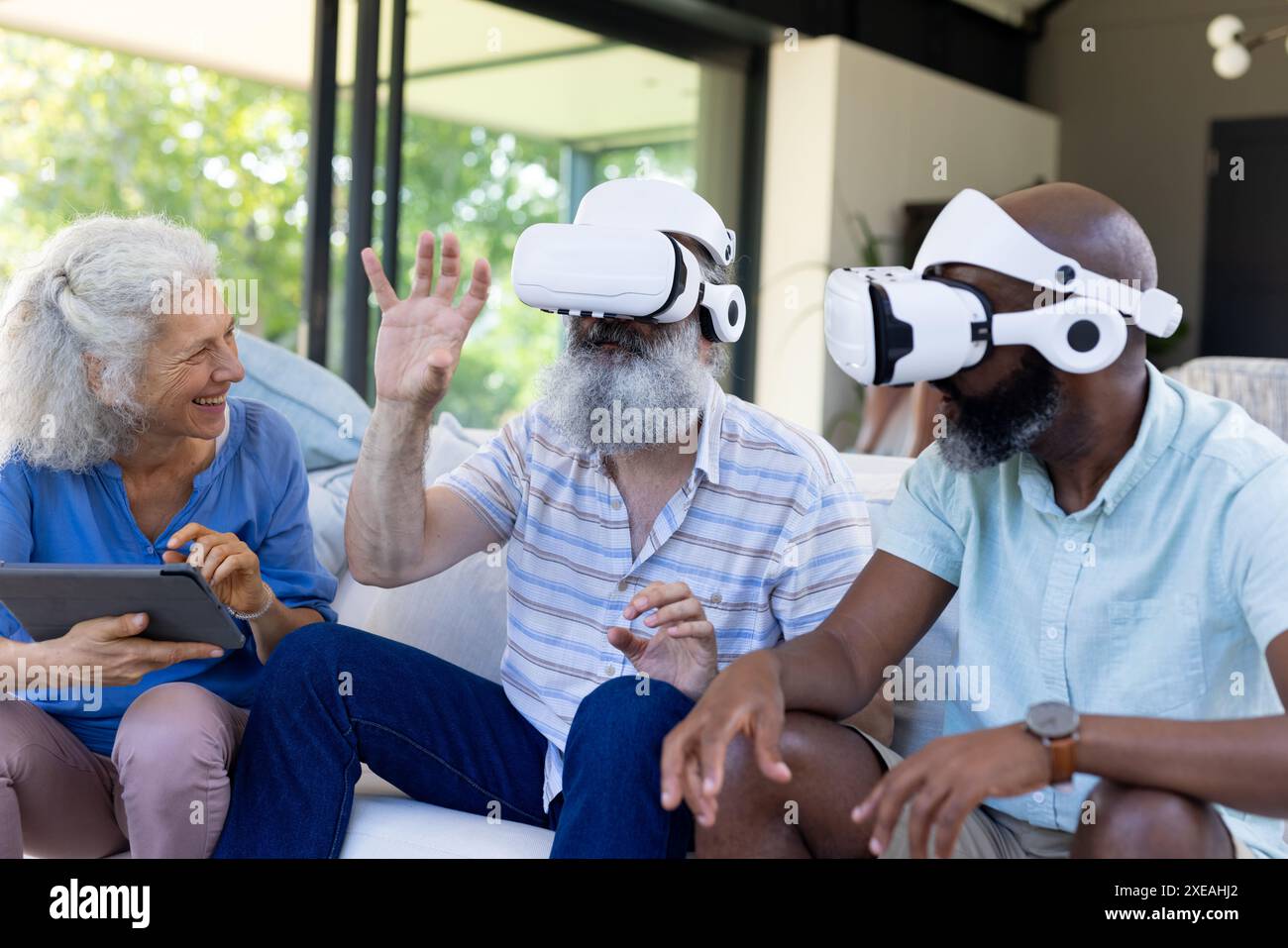 Zu Hause nutzen verschiedene ältere Freunde VR-Headsets und -Tablets und genießen die Technologie Stockfoto