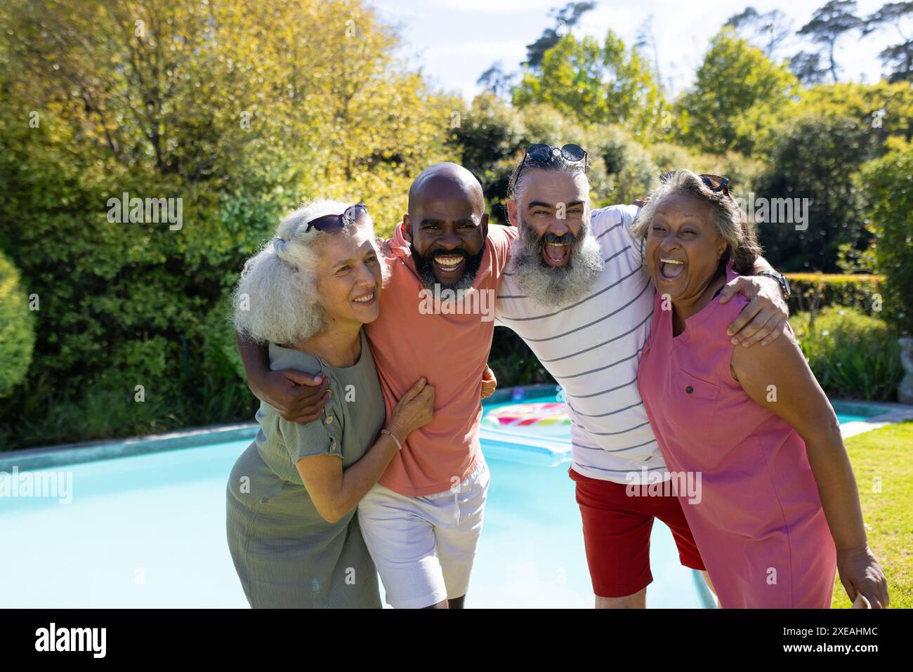 Verschiedene ältere Freunde umarmen und lächeln am Swimmingpool im Freien Stockfoto