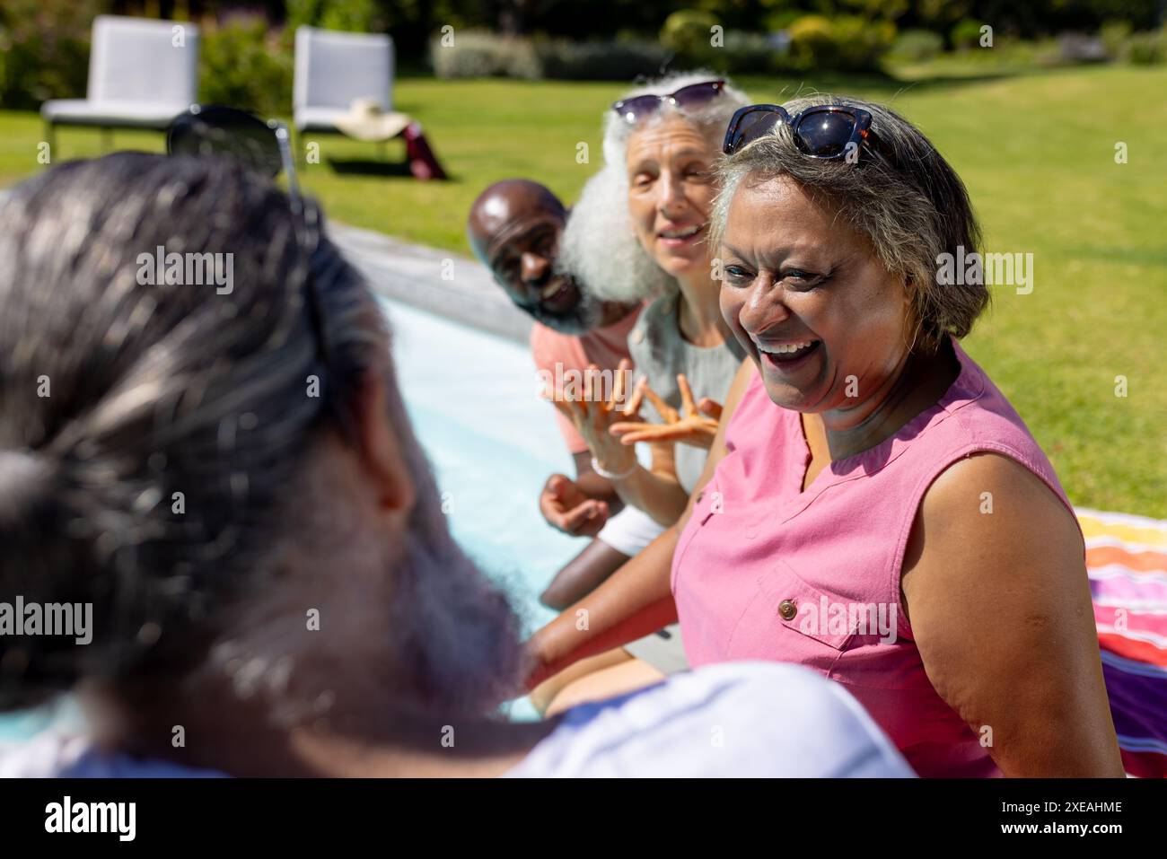 Gruppe von älteren Freunden lacht und entspannt am Pool an sonnigen Tagen Stockfoto