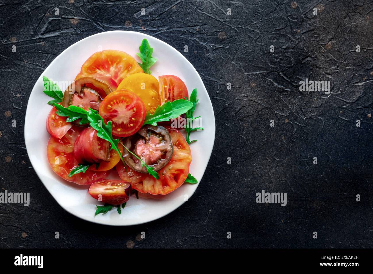 Frische Tomaten und Rucolasalat. Eine Vielzahl von Tomaten verschiedener Art Stockfoto