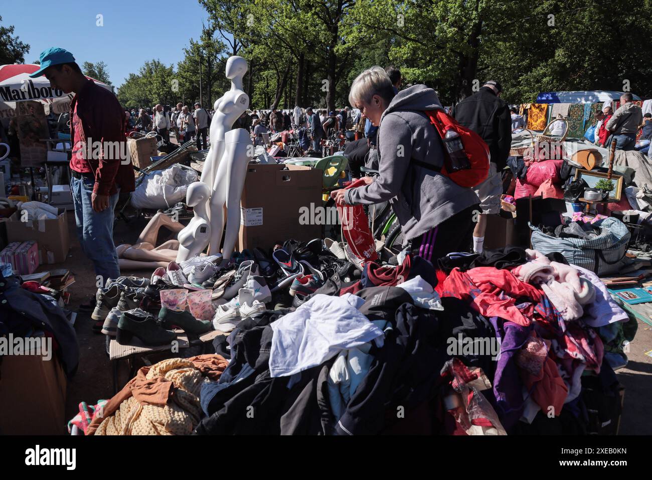 Die Menschen graben sich durch Anhäufungen verschiedener Kleidung und weißer Schaufensterpuppen, die in der Nähe auf dem Flohmarkt in Udelnaya in St. Petersburg stehen. Der Flohmarkt in Udelnaya in St. Petersburg ist ein beliebter Ort für Liebhaber von Antiquitäten und einzigartigen Fundstücken. Hier finden Sie verschiedene Artikel: Antiquitäten, Vintage-Kleidung, Schuhe, Sammlerstücke, Souvenirs und vieles mehr. Der Markt ist bekannt für seine gemütliche Atmosphäre und die Möglichkeit, einzigartige Artikel zu konkurrenzfähigen Preisen zu kaufen. Dies ist ein großartiges Ziel für ausländische Touristen, die lokale Kultur und Geschichte durch einzigartige Gegenstände und Antiquitäten erleben möchten. (Foto von A Stockfoto