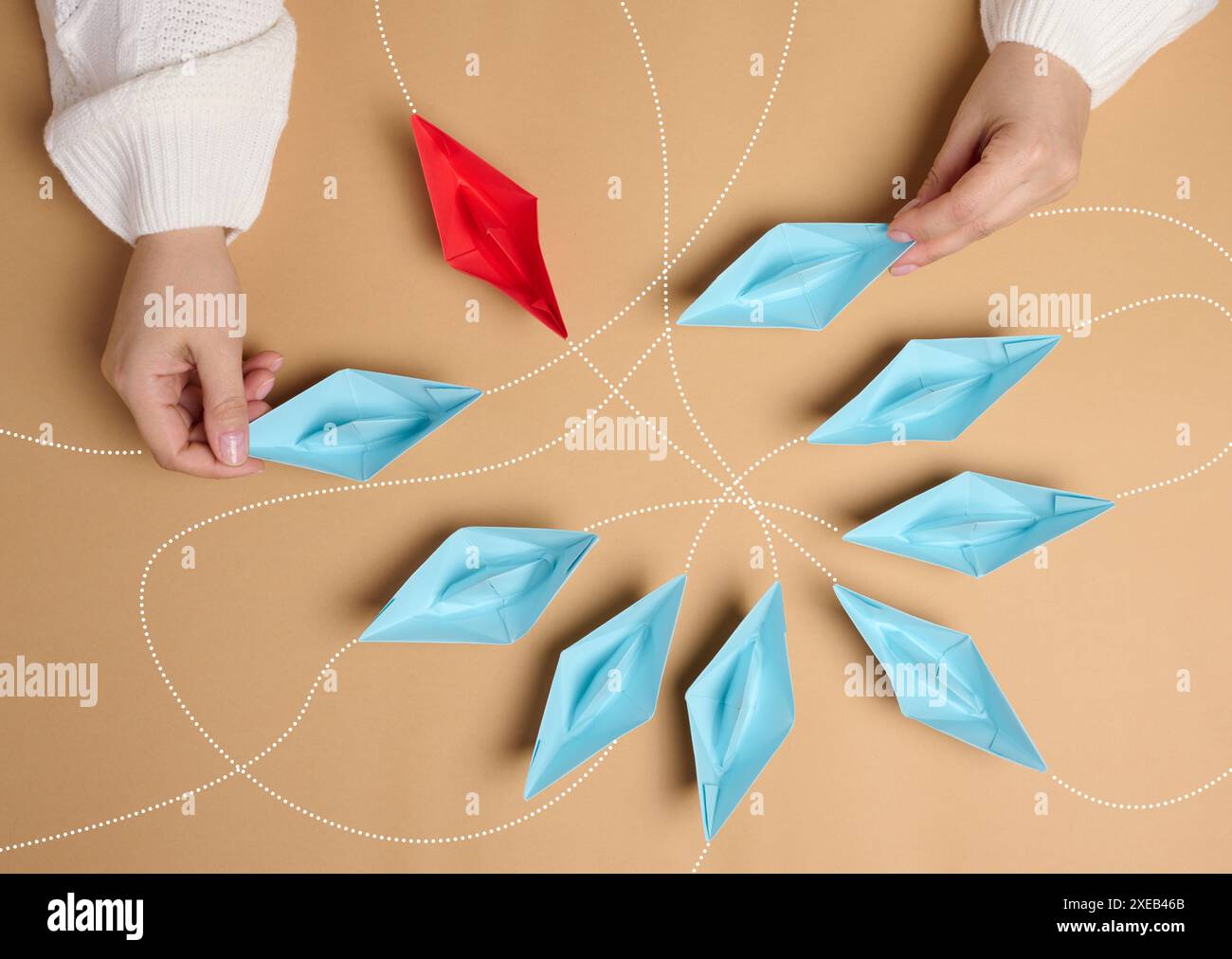 Papierboote mit verschiedenen Flugbahnen in womanâ Hand auf braunem Hintergrund Stockfoto