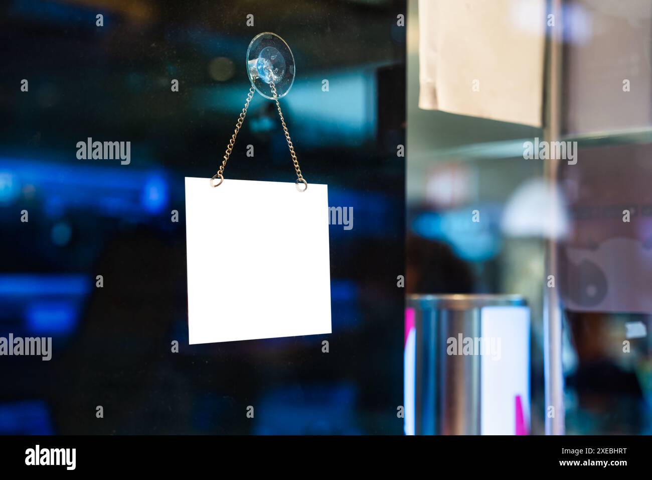 Leeres weißes Plastikschild hängt am Glasfenster im Einkaufszentrum Stockfoto