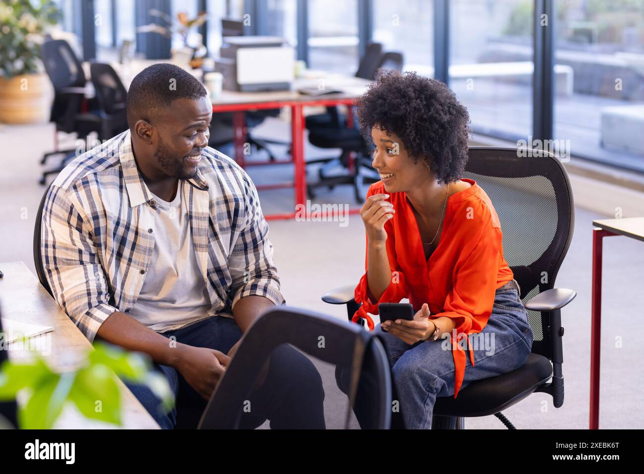 Afroamerikanische Geschäftskollegen diskutieren über Arbeit, lächeln in modernen Büros Stockfoto