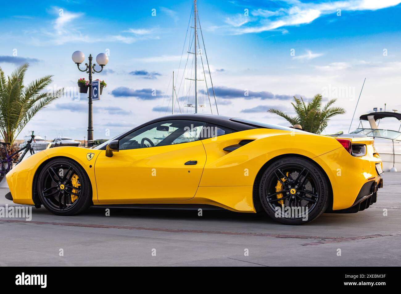 Gelber Sportwagen Ferrari Spider auf Yachthafen bei Sonnenuntergang Stockfoto