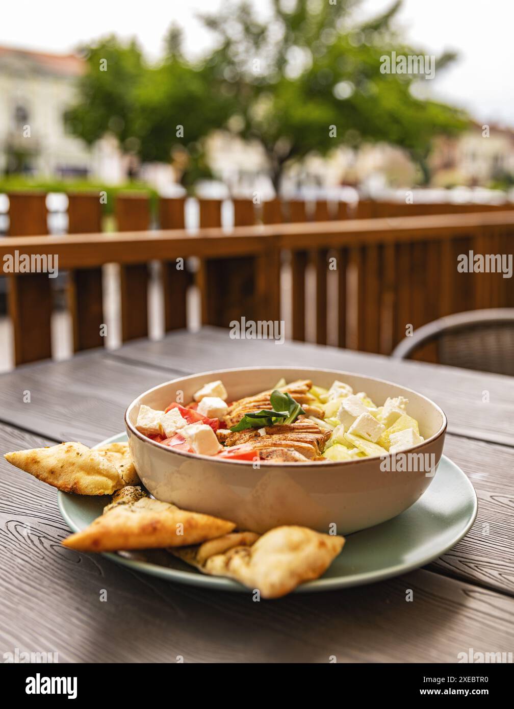 Köstlicher griechischer Salat mit Huhn und Pitabrot auf der Terrasse Stockfoto