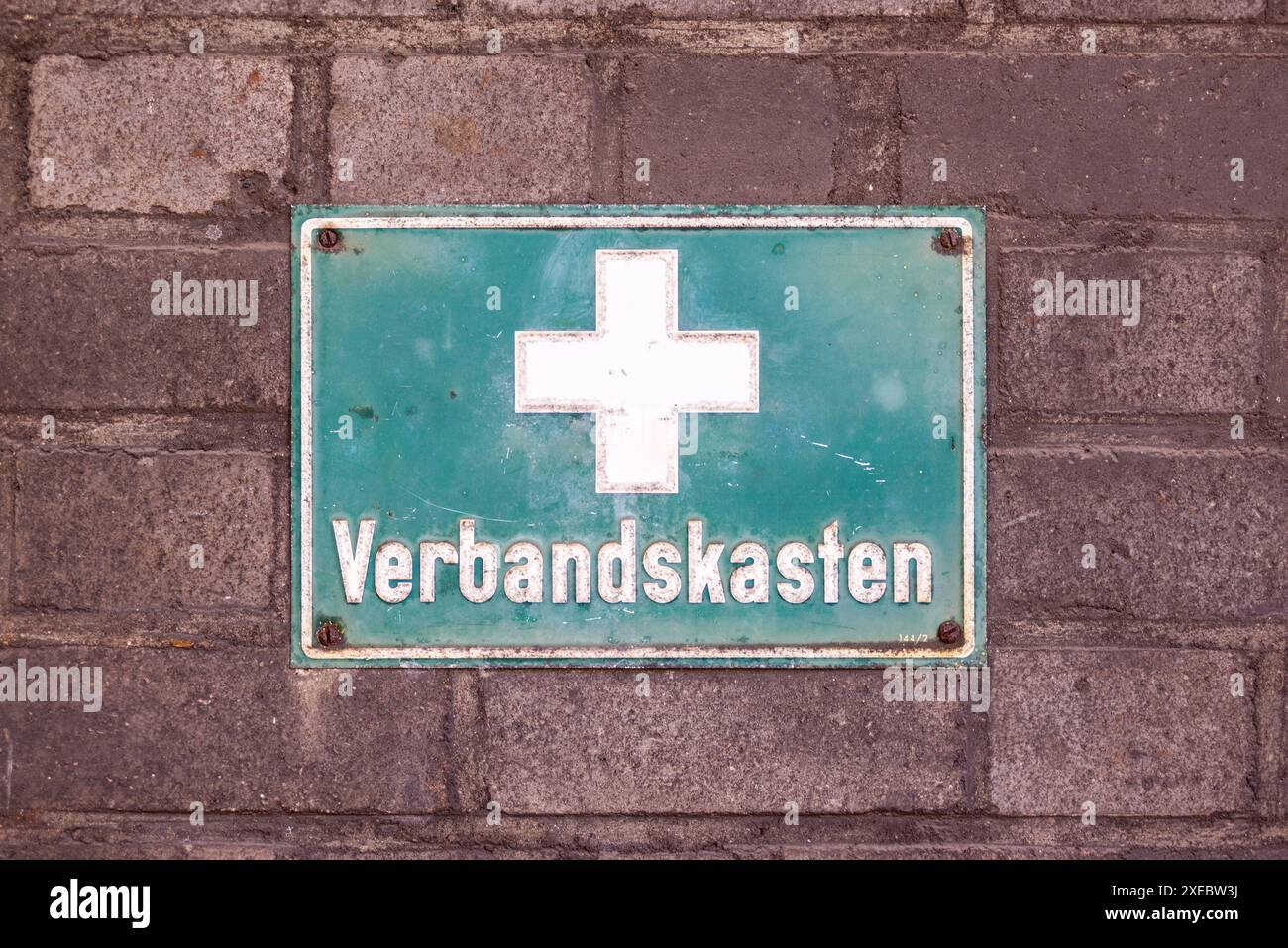 Schreiben an der Wand einer alten Hüttenanlage in Deutschland - erste-Hilfe-Kasten. Grüne Platte mit weißem Kreuz und Inschrift in deutscher Sprache. Stockfoto