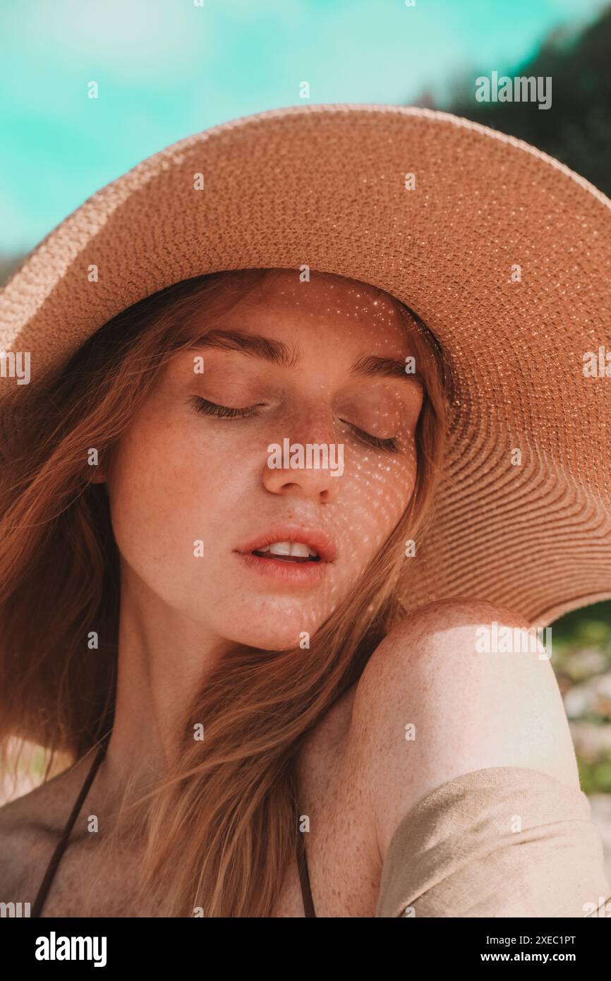 Porträt einer jungen attraktiven rothaarigen Frau mit Sommersprossen mit Strohhut Stockfoto
