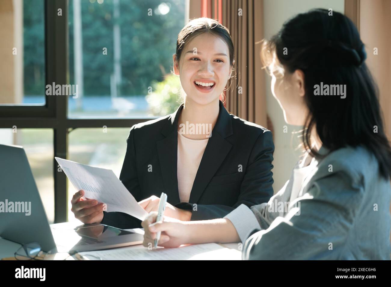 Zwei Frauen in Business-Anzügen reden miteinander Stockfoto