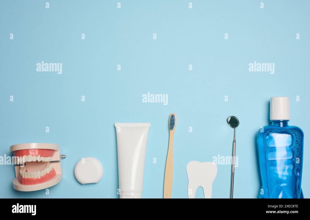 Mundspülung, Zahnpasta, Zahnseide und medizinischer Spiegel auf blauem Hintergrund, Mundhygiene. Stockfoto